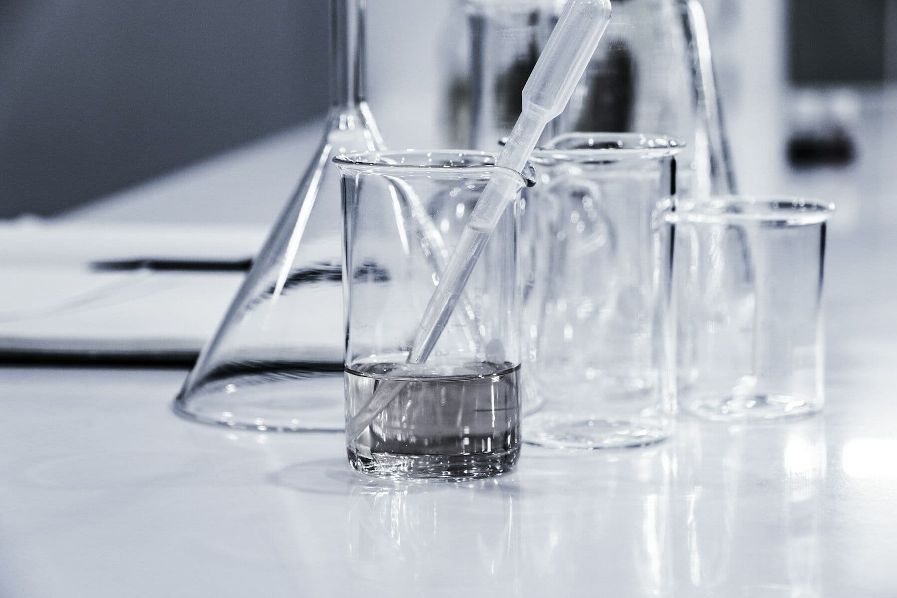 Laboratory beakers, a flask and a pipette on a white bench