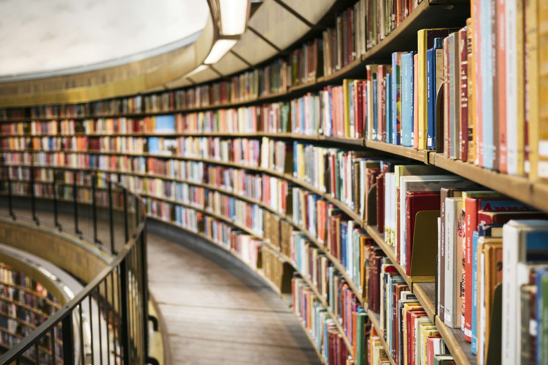 Curved library shelves full of books along a railed walkway