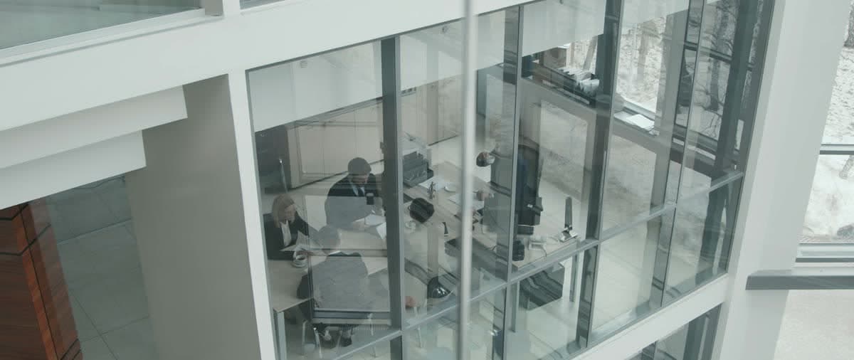 Colleagues meeting at a desk inside a glass-walled office